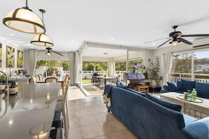 A spacious living area with a dining table, blue sofa, and a piano.