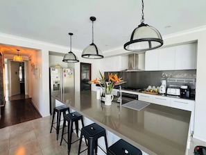 A modern kitchen with a central island, bar stools, pendant lighting, and a refrigerator. - Amazon Artistry 5 bedrooms Full House (Upper Kedron)