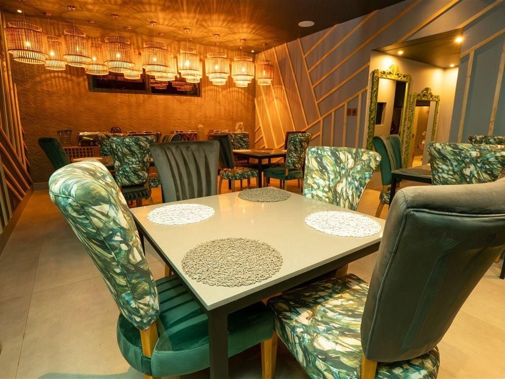A dining area with a table set for four, surrounded by chairs with a leaf pattern upholstery.