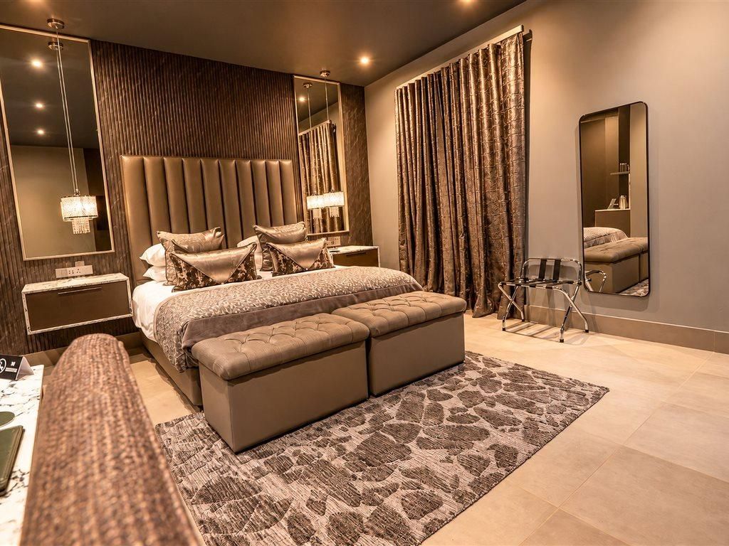 Een moderne slaapkamer met een groot bed, een nachtkastje, een spiegel en een gordijn.