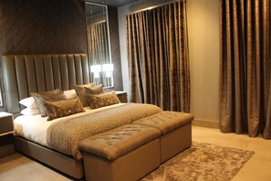 Een moderne slaapkamer met een groot bed, een hoofdeinde en een bankje.