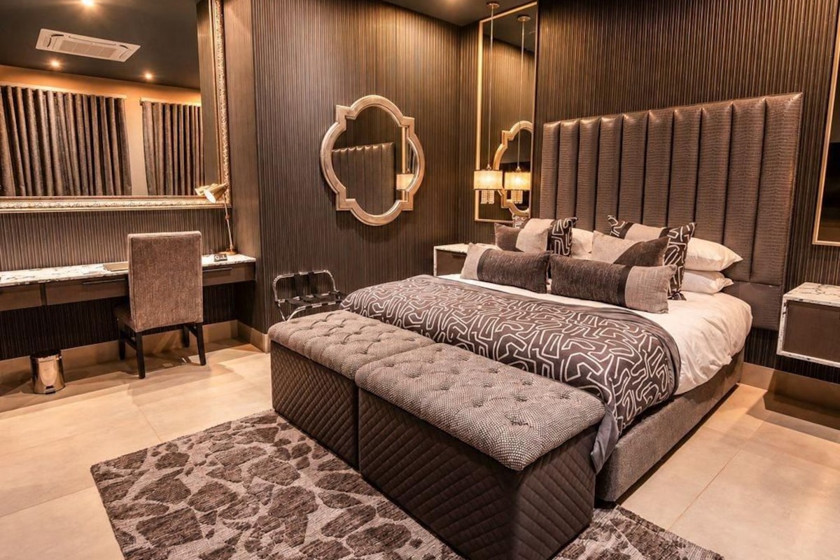 A modern bedroom with a large bed, a desk, and a chair.