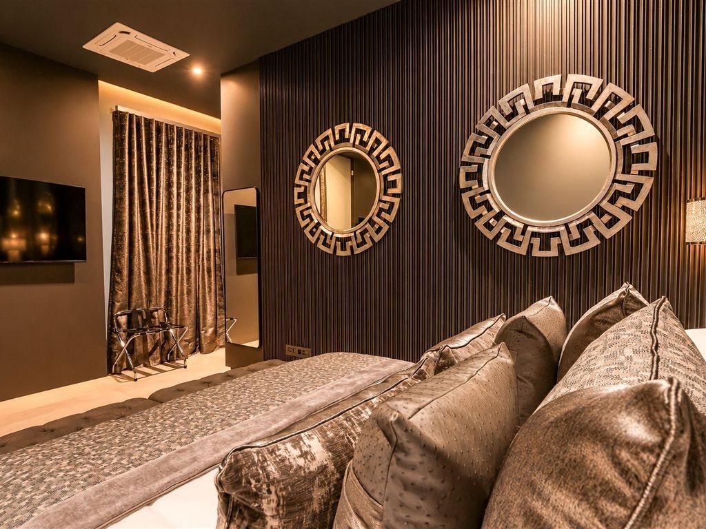 A modern room with a sofa, two wall-mounted mirrors, a television, and a curtain.