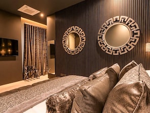 A modern room with a sofa, two wall-mounted mirrors, a television, and a curtain.
