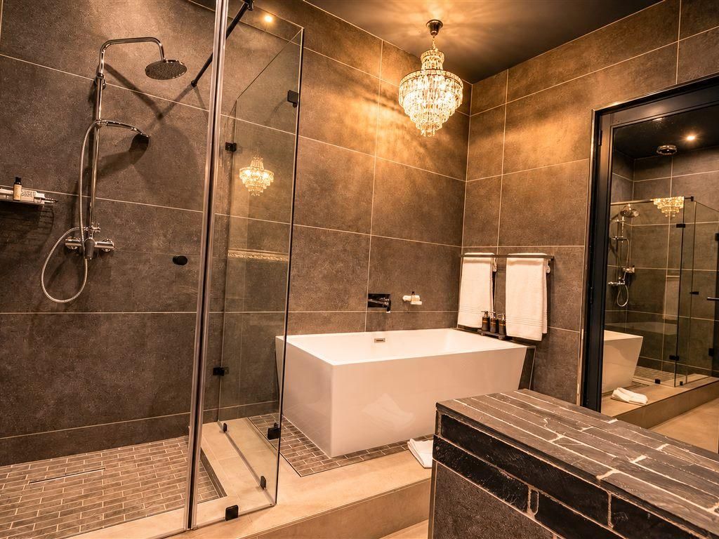 A modern bathroom with a glass-enclosed shower, a freestanding bathtub, and a large mirror.