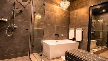 A modern bathroom with a glass-enclosed shower, a freestanding bathtub, and a large mirror.