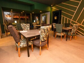 A dining area with multiple tables and chairs, a patterned wall, and a green accent wall.