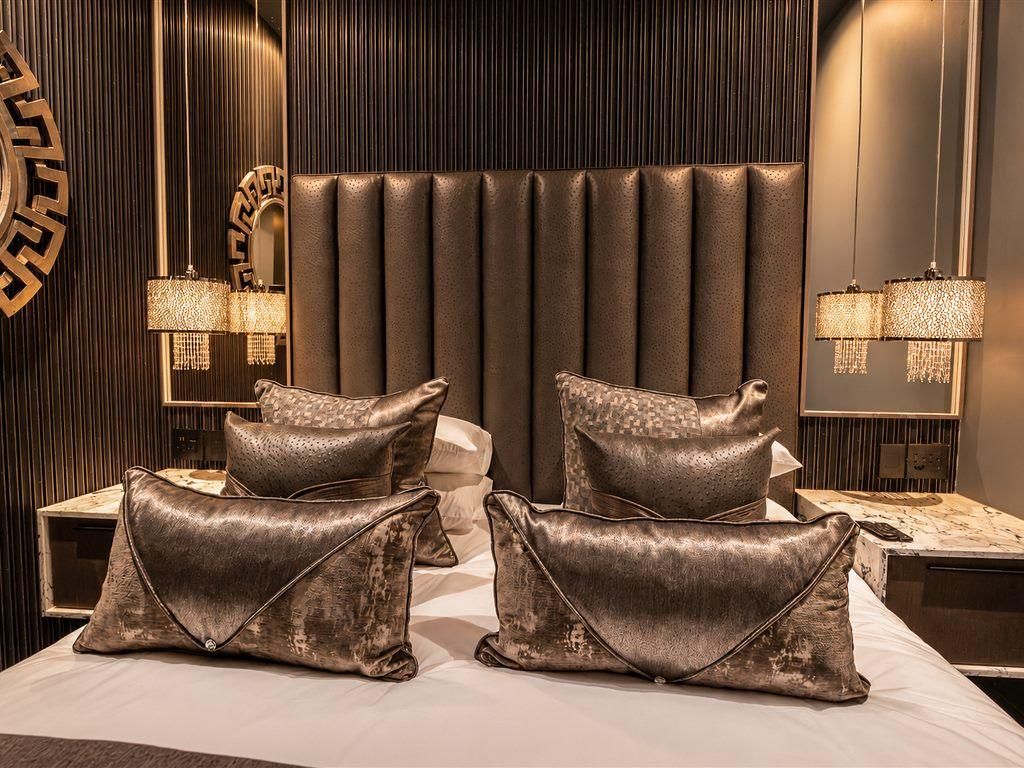 A modern bedroom with a tufted headboard, two bedside lamps, and decorative pillows.