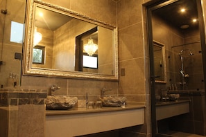 Een badkamer met een grote, sierlijke spiegel, een kroonluchter en een moderne douche.