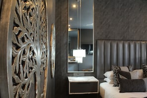 Een moderne slaapkamer met een groot bed, een decoratief paneel en een hanglamp.