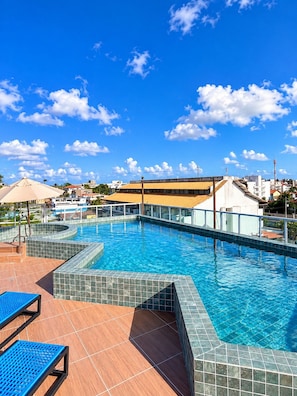 Ein Pool mit gefliesten Rändern, Liegestühlen und blauem Himmel.