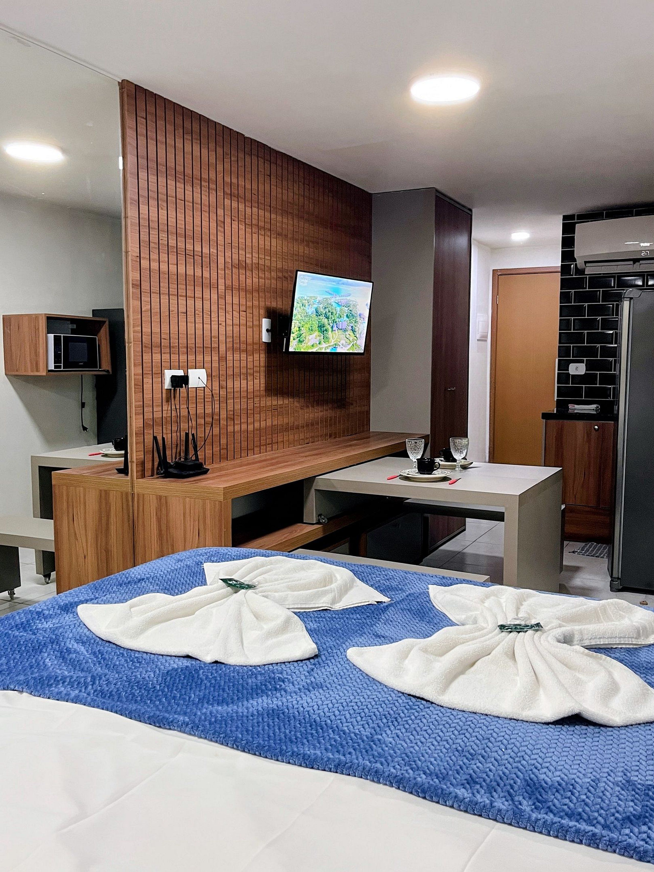 Ein Hotelzimmer mit einem Bett, einem an einer Holzpaneelwand montierten Fernseher, einer Mikrowelle und einem Kühlschrank.
