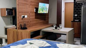 Ein Hotelzimmer mit einem Bett, einem an einer Holzpaneelwand montierten Fernseher, einer Mikrowelle und einem Kühlschrank.