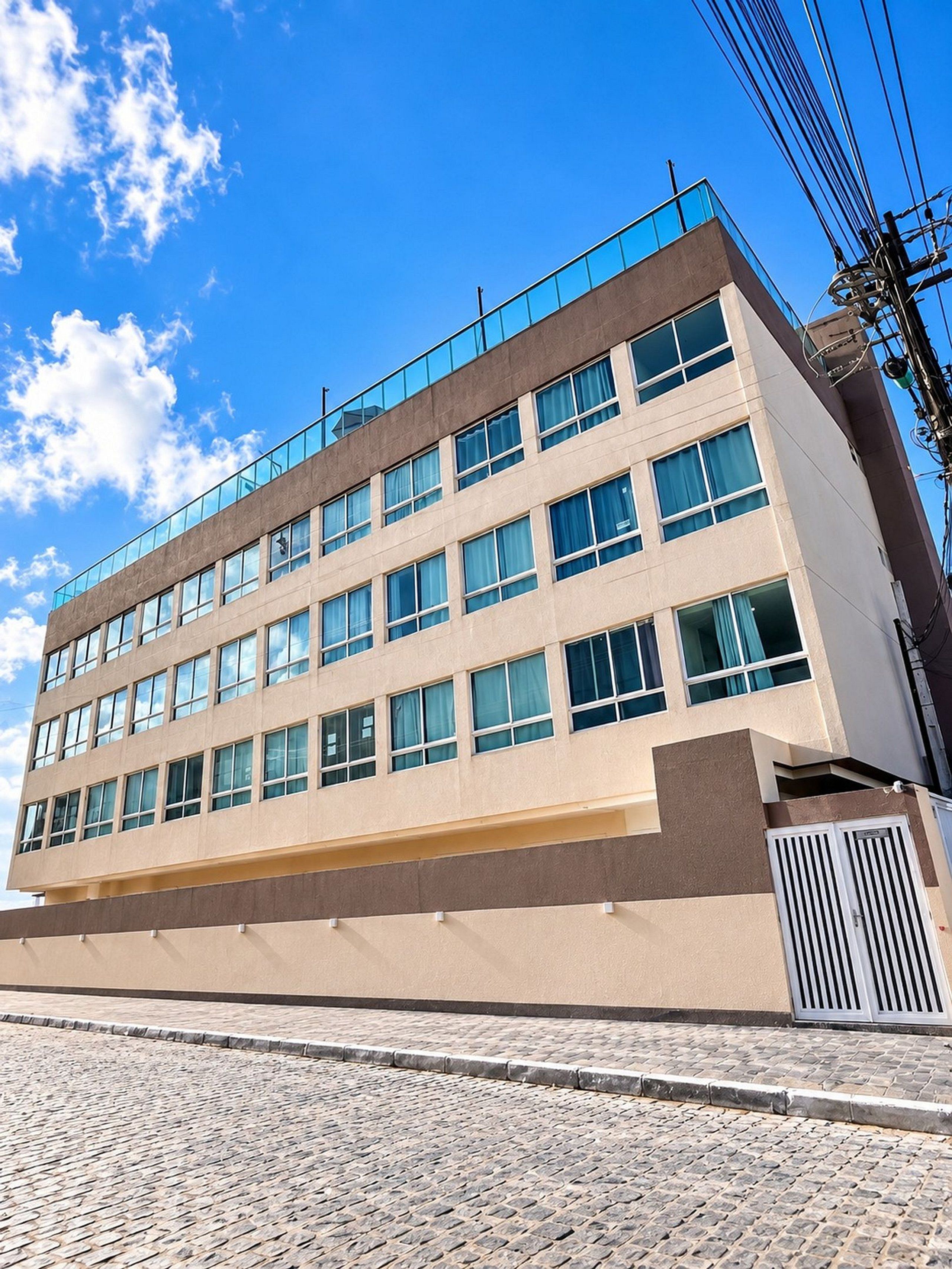 Ein mehrstöckiges Gebäude mit schlichter Fassade, großen Fenstern und einem Balkon im oberen Stockwerk.