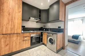 A compact kitchen with built-in appliances, a washing machine, and a small oven. - Modern 1-Bedroom Apartment in Casablanca | Stylish & Comfortable (Casablanca)