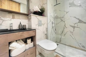 A bathroom with a marble sink, toilet, and glass-enclosed shower. - Modern 1-Bedroom Apartment in Casablanca | Stylish & Comfortable (Casablanca)
