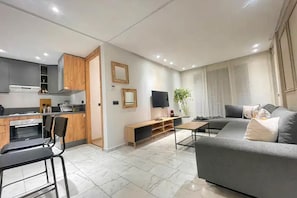 A modern kitchen with a dining area, a sofa, and a TV. - Modern 1-Bedroom Apartment in Casablanca | Stylish & Comfortable (Casablanca)