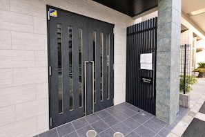 A modern building entrance with a dark door, a vertical metal gate, and a sign indicating 'Regalo shibakura.' - SLEEPLAB THE STAY Shibaura (Minato)