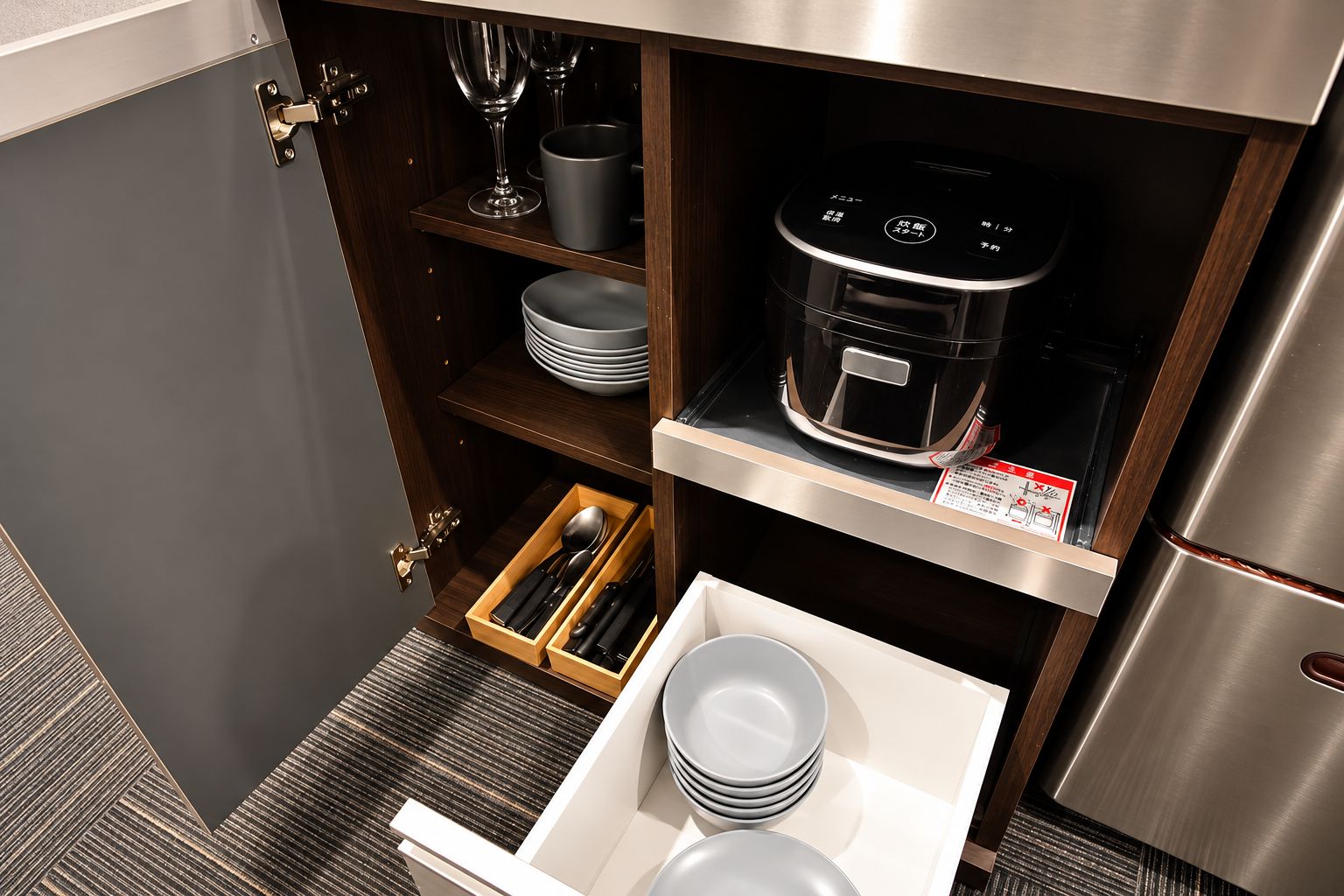A compact kitchen with a built-in oven, a microwave, and a stainless steel refrigerator.