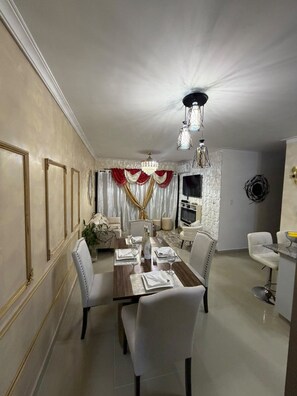 Uma sala de jantar com um candelabro, uma televisão e uma parede de pedra.