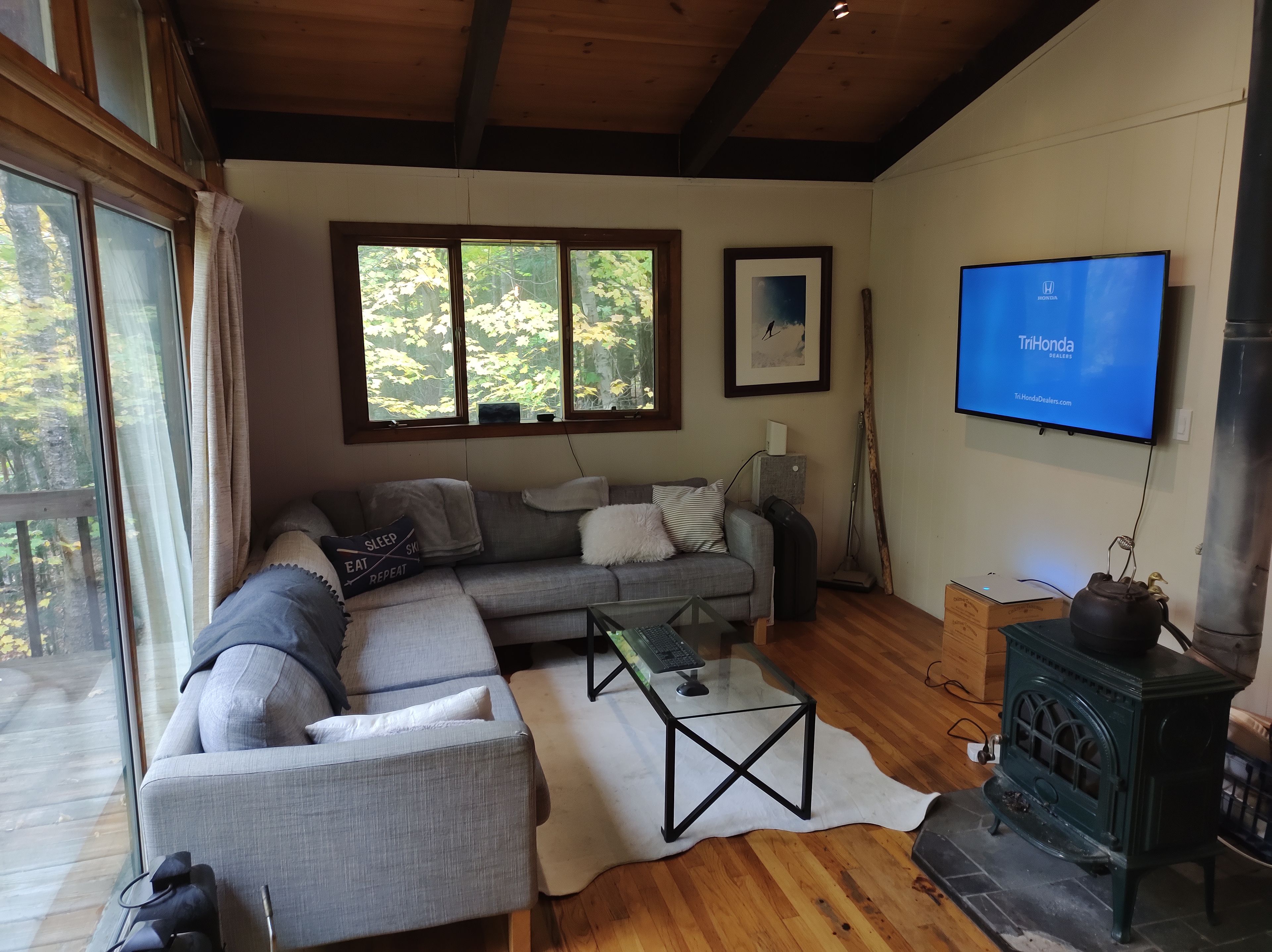 A living room with a sectional sofa, a television, a fireplace, and a window with a view of trees.