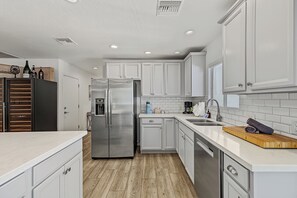 Une cuisine moderne avec des meubles blancs, un réfrigérateur en acier inoxydable et un plan de travail en bois.