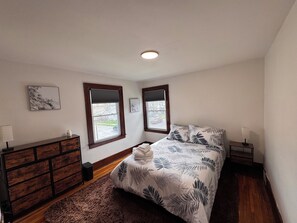 A bedroom with a bed, two windows with blinds, a dresser, and a nightstand with a lamp. - 3-bedroom house minutes from the U of R, URMC and Airport (Rochester)