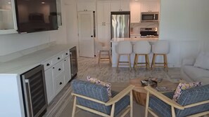 A modern living room with a sofa, two armchairs, a coffee table, and a TV mounted on the wall. - GulfDrift— Beachfront Boca Grande — On the Gulf (Boca Grande)