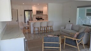 A modern kitchen with white cabinets, a central island with bar stools, a built-in microwave, and an oven. - GulfDrift— Beachfront Boca Grande — On the Gulf (Boca Grande)