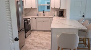 Una cucina moderna con mobili bianchi, un piano di lavoro in marmo, forno integrato e una grande isola con posti a sedere.