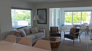 Ein Wohnzimmer mit einer Couch, Stühlen, einem Couchtisch und einem Essbereich mit Tisch und Stühlen.