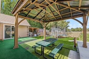 An outdoor patio area with a covered seating area, artificial turf, and playground equipment. - 4 Bedroom 3 Bathroom Great Boise Location! Easy Access-Shopping & Restaurants! (Boise)