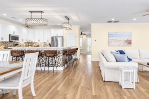 A modern kitchen with white cabinets, a central island with bar stools, and pendant lighting. - Ocean Views-Sleeps 24-Pool-Steps to Beach (Atlantic Beach)