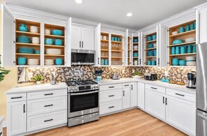 A modern kitchen with white cabinets, a stainless steel stove, and blue and white dishware. - Ocean Views-Sleeps 24-Pool-Steps to Beach (Atlantic Beach)