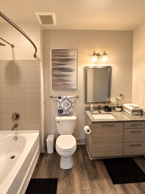 Une salle de bain moderne équipée d’une baignoire, de toilettes, d’un lavabo et d’un meuble-lavabo.