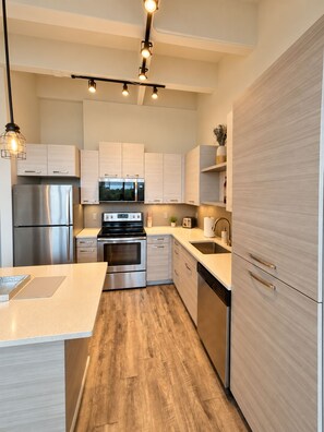 Une cuisine moderne dotée d’appareils électroménagers en acier inoxydable, de meubles en bois et d’un îlot central.