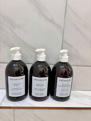 Three bottles of Sachajuan hair and body wash on a tiled surface. - Second Floor Studio | 0.3 Miles from SFA (Nacogdoches)
