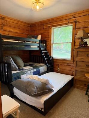 Ein Schlafzimmer einer Holzhütte mit Etagenbetten, einem Schreibtisch und einer Kommode.