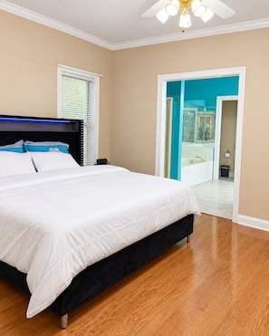 A bedroom with a large bed, a nightstand, a ceiling fan, and a view of a bathroom through an open door. - The Willow at Brenhaven, Sleeps 6 (Brandon)