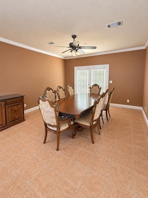 A dining room with a large wooden table surrounded by ornate chairs, a ceiling fan, and a window with blinds. - The Willow at Brenhaven, Sleeps 6 (Brandon)