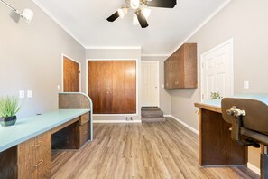 A room with a wooden floor, a desk with drawers, a ceiling fan, and a door with a wooden panel. - 6BD/3.5BA Wine Country Home w/ Solar Heated Pool + Billiards + BBQ (Santa Rosa)