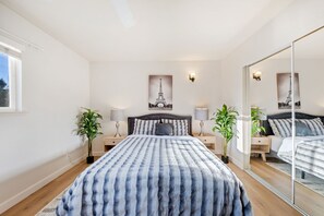 A bedroom with a large bed, two bedside tables, a mirror, and two potted plants. - 6BD/3.5BA Wine Country Home w/ Solar Heated Pool + Billiards + BBQ (Santa Rosa)