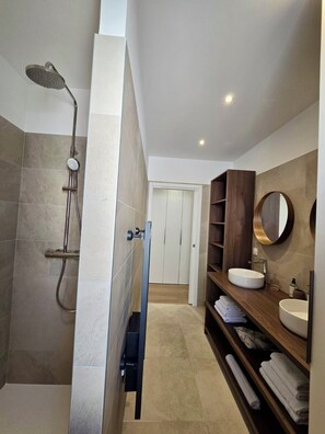 Een moderne badkamer met een inloopdouche, een wastafelmeubel en een houten plankensysteem.
