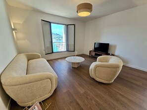 Un soggiorno moderno con un divano, due poltrone, un tavolino da caffè e una TV.