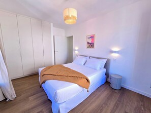 Un dormitorio con cama, armario, mesita de noche y un póster en la pared.