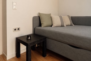 A modern living room with a grey sofa, a small black side table, and a single candle. - Vrbo Property (Starnberg)