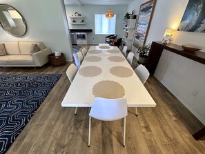 Un comedor con una mesa larga, sillas y un tapete estampado.