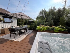 Una terraza con hidromasaje, mobiliario exterior y una sombrilla.