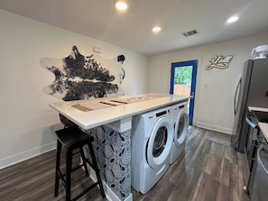 A laundry area with a washing machine, a sink, and a bar stool. - Tobin Hill Casita w/ Private Hot Tub near Pearl (San Antonio)