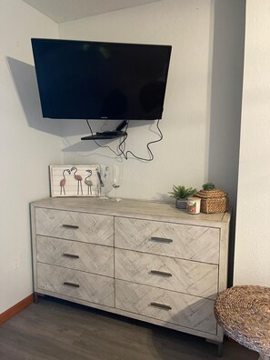Un televisor de pantalla plana fixat a la paret sobre un moble de fusta amb dibuix de guia de peix i calaixos.